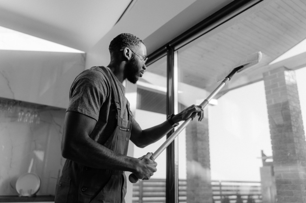 Who we are image of man cleaning a window Man cleaning window